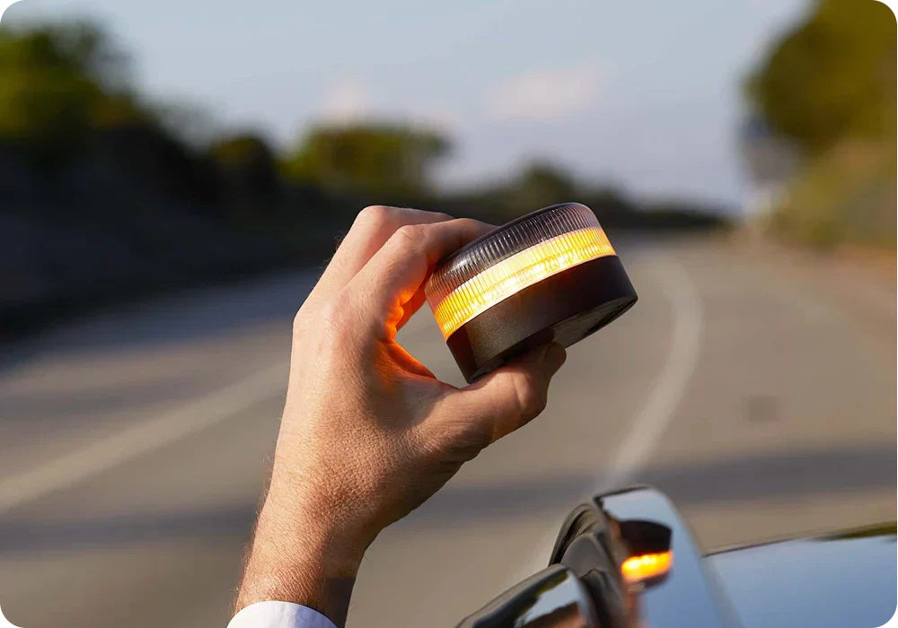 Conductor colocando Baliza V16 conectada obligatoria 2026.